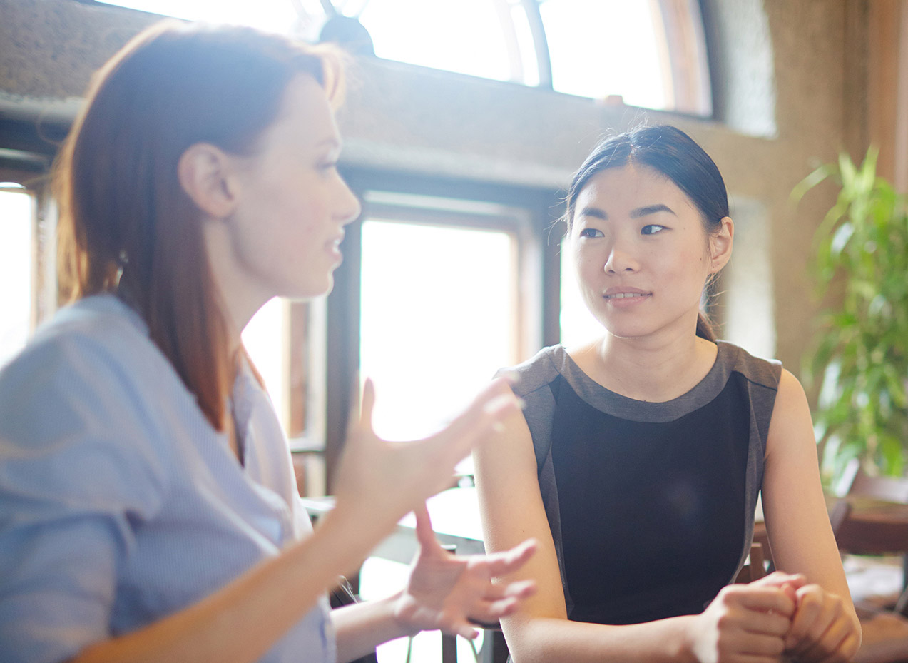 two women talking at a table