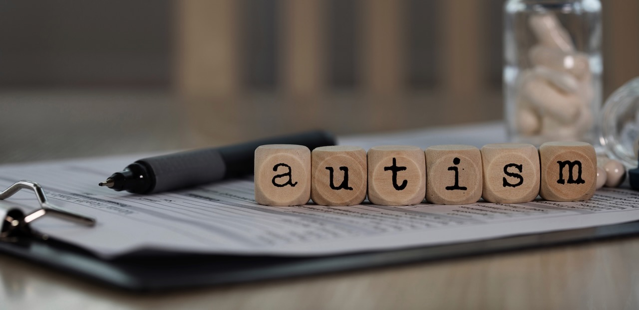 Mentoring autistic people. Word AUTISM composed of wooden dice.