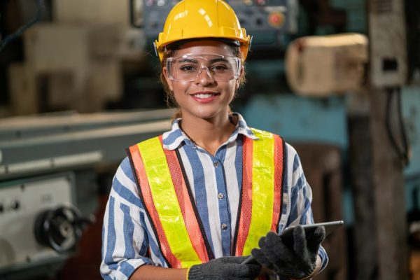 Smiling female wearing safety jacket, glasses and hard hat.