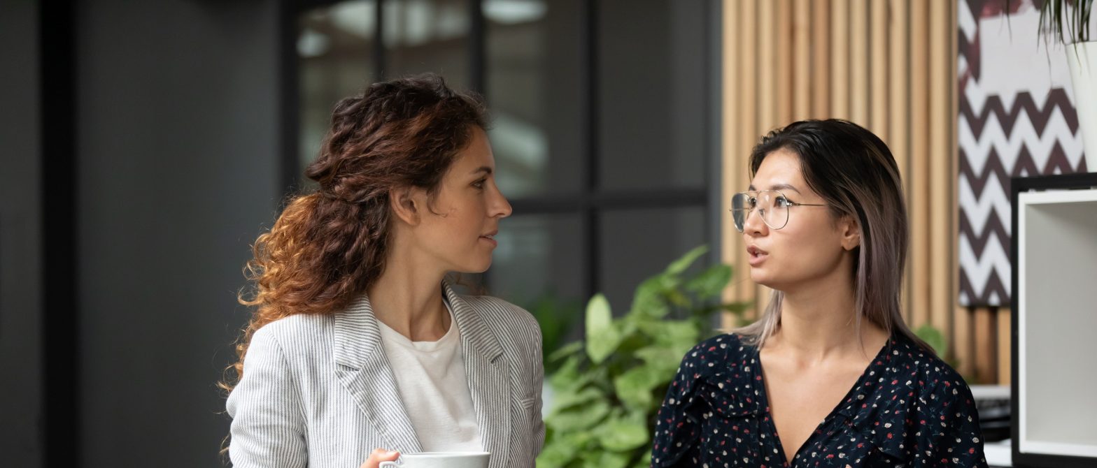 Two female colleagues are deep in conversation in the office