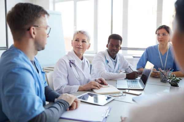 A group of medical colleagues are sitting at a conference table and having a discussion.