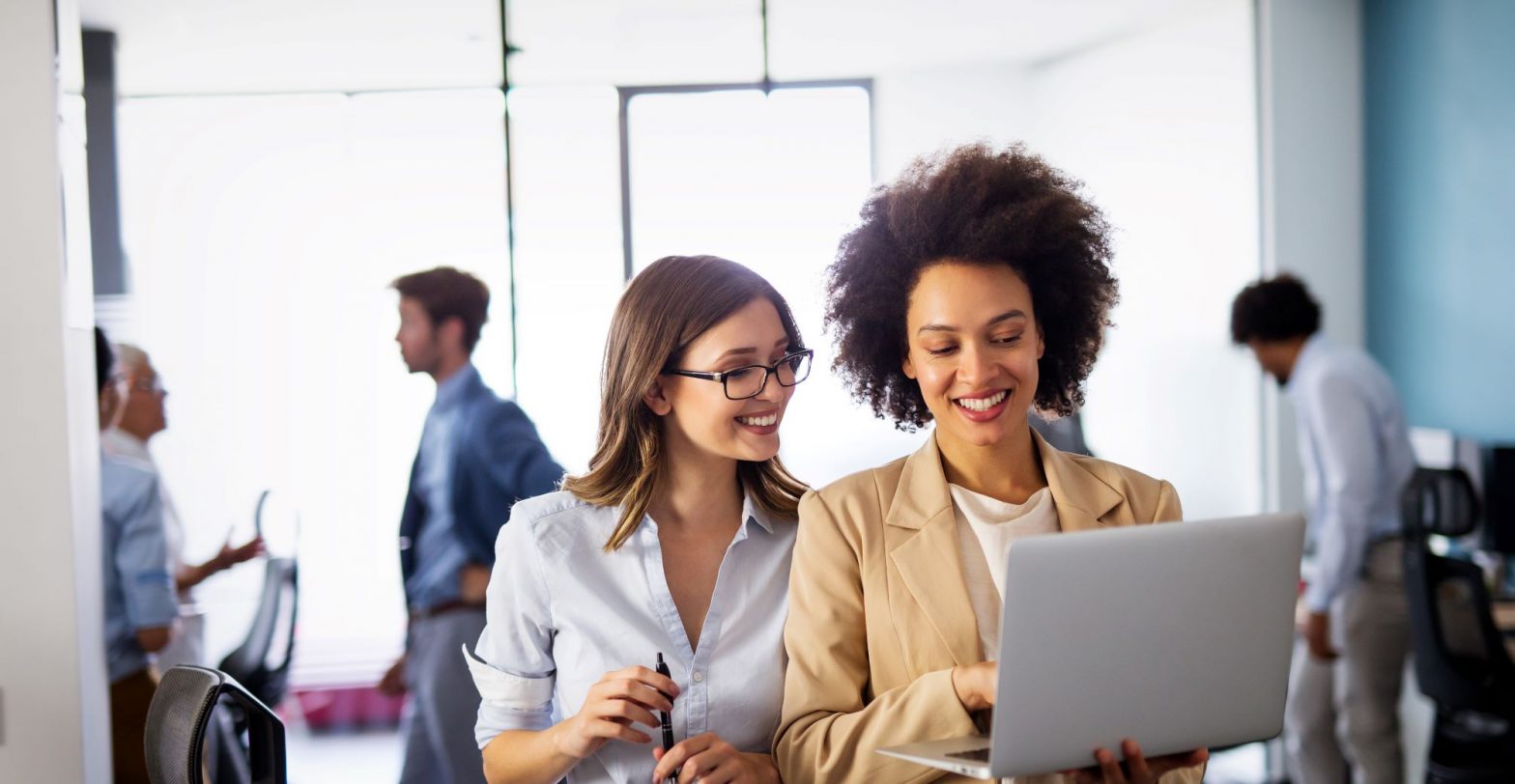 Female business colleagues collaborating and discussing information on a laptop.