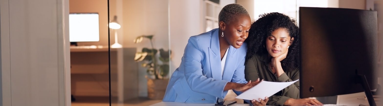 Business woman mentoring worker at night in a modern office