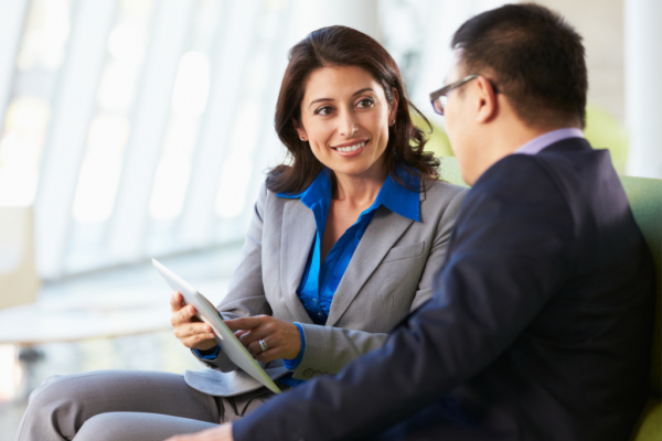 A female mentor is showing her male mentee something on her tablet computer