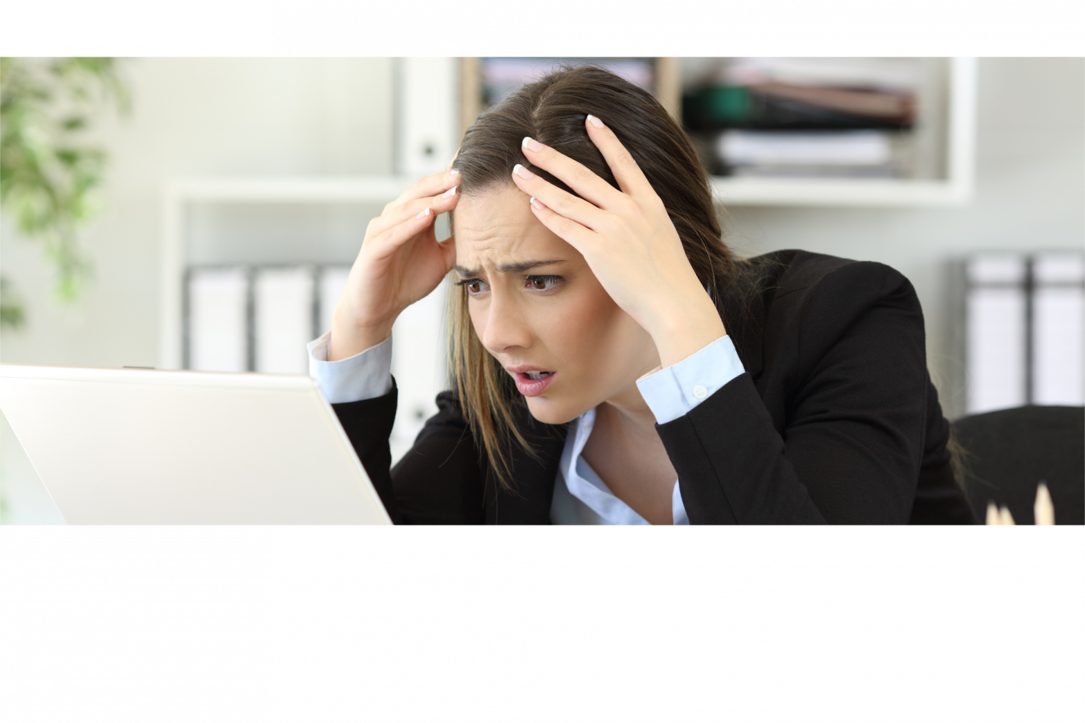 Female business woman is looking frustratedly at her laptop with her head in her hands.