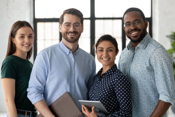 Two male and two female business people smiling and posing together.