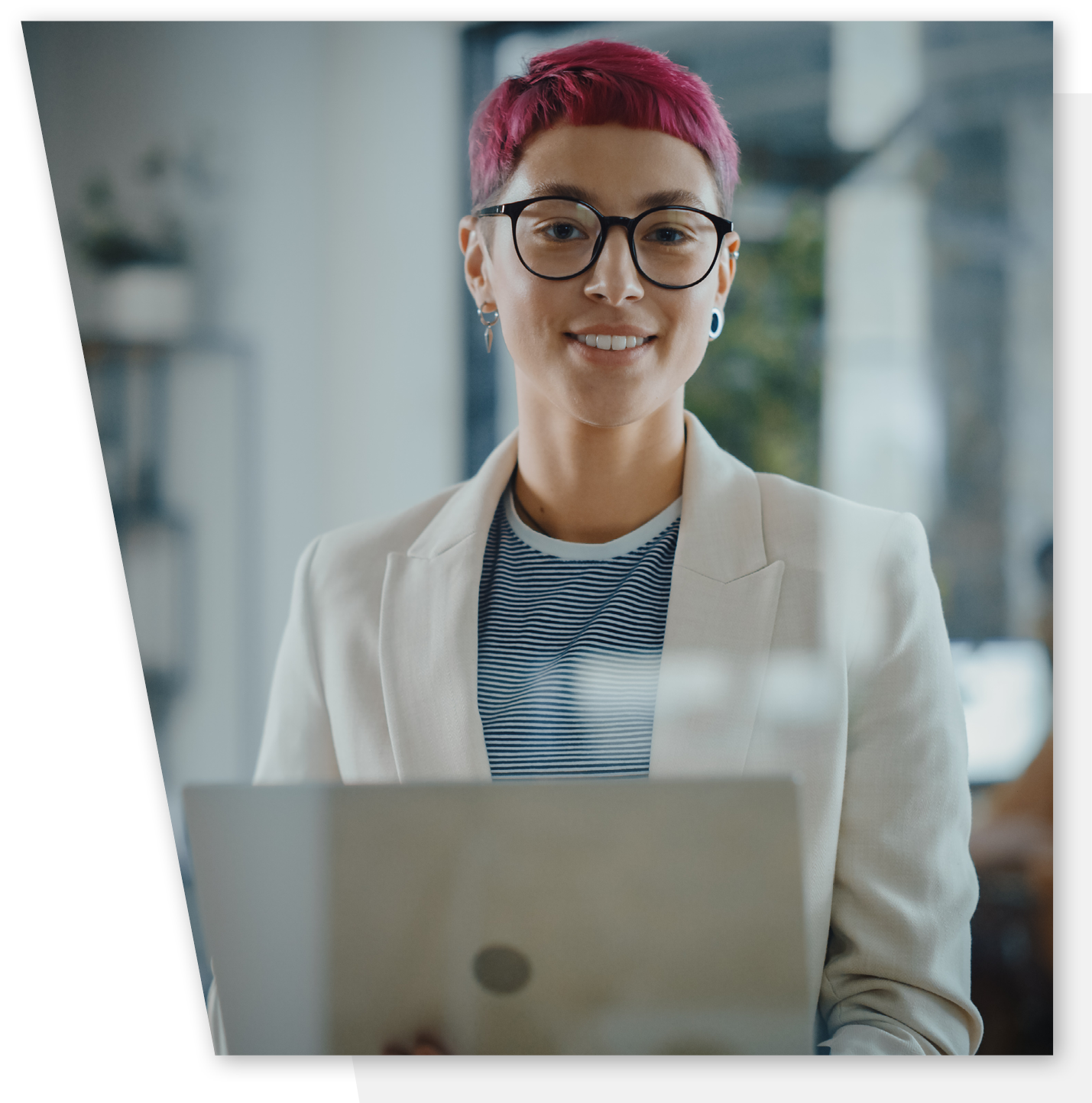 Young female with glasses and pink hair is sitting behind a laptop